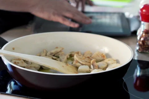 Man cooking chicken and checking recipe on tablet computer in kitchen  NTSC Vídeos de archivo 49550193