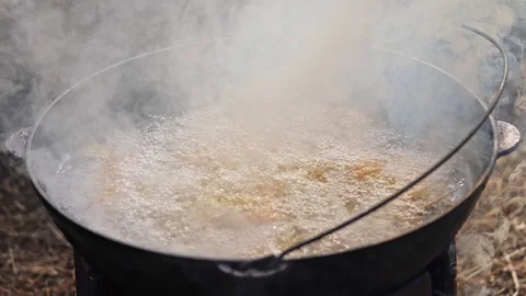 A man is cooking dinner in a tub at a fire Stock Footage 126862011