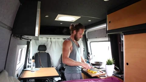 Man cooking inside his camper van Stock Footage 135381357