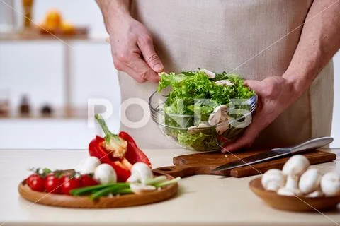 Man cooking at kitchen making healthy vegetable salad, close-up, selective focus Stock Photos