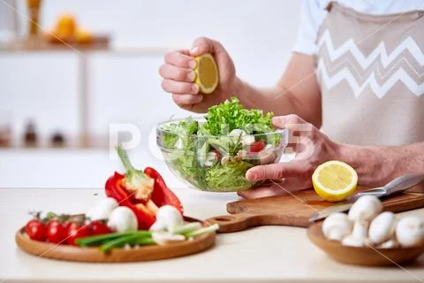 Man cooking at kitchen making healthy vegetable salad, close-up, selective focus Stock Photos