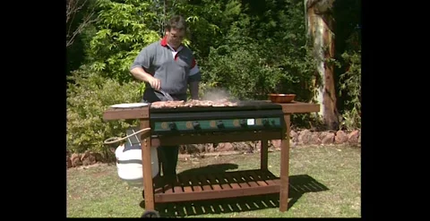Man Cooking Meat on Aussie BBQ 1990s Stock Footage 317804279