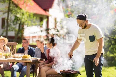 Man cooking meat on barbecue grill at summer party Stock Photos