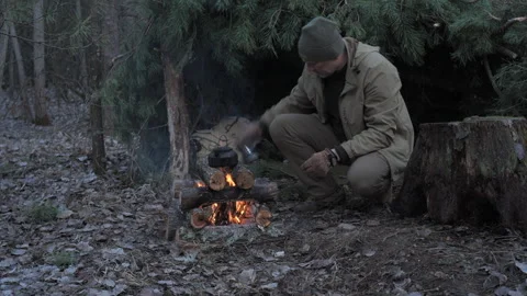 Man cooking over campfire in the forest Stock Footage 307857953