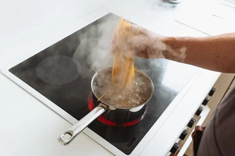 Man cooking spaghetti in kitchen Stock Photos