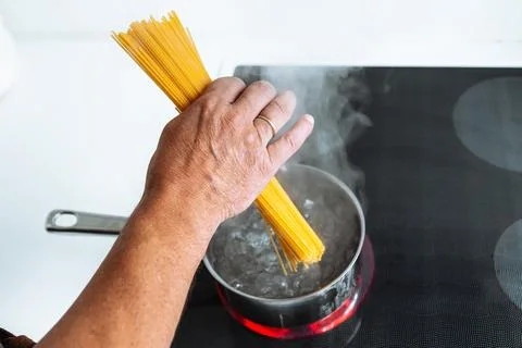 Man cooking spaghetti in kitchen Stock Photos