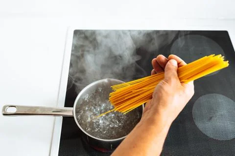 Man cooking spaghetti in kitchen Stock Photos