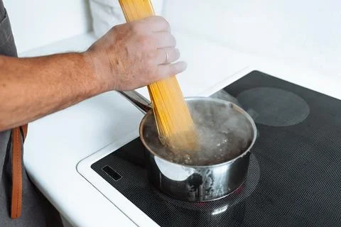 Man cooking spaghetti in kitchen Stock Photos