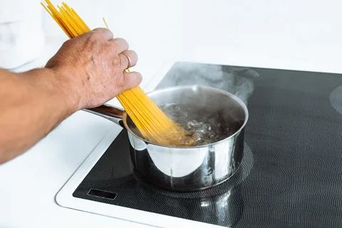 Man cooking spaghetti in kitchen Stock Photos