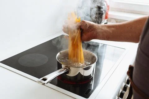 Man cooking spaghetti in kitchen Stock Photos