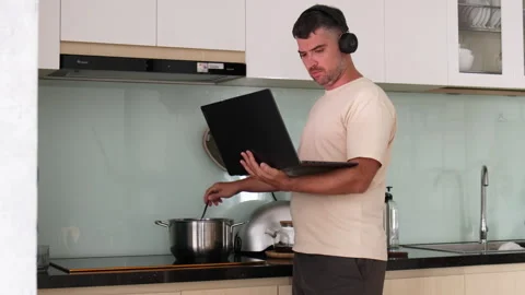 Man is cooking while on a video conference. Stock Footage 311052560