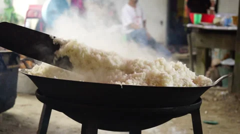 Man cooking white rice using paddle stick in a big wok, cauldron Stock Footage 34975117