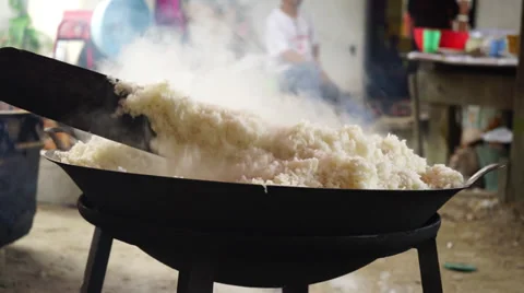 Man cooking white rice using paddle stick in a big wok, cauldron Stock Footage 35006726