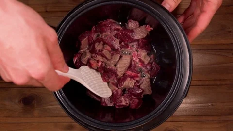 A man cooks beef stew in a slow cooker stir with a spoon Stock Footage 129101145