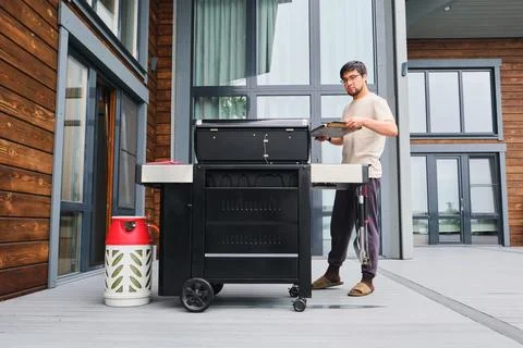 A man cooks on a grill on the veranda. Stock Photos
