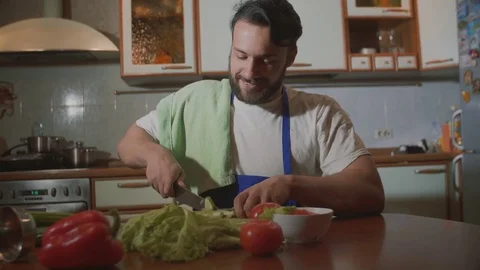 A man cooks in the kitchen he cuts vegetables Stock Footage 71642077