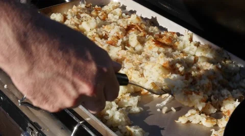 A man cooks potato hash browns while camping Stock Footage