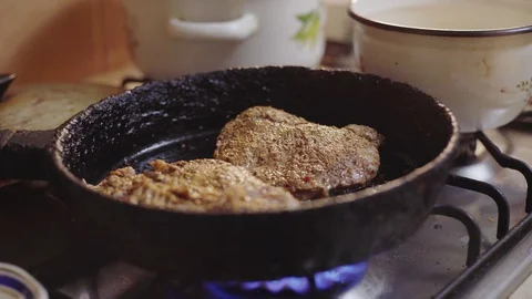 A man cooks a steak in a pan in the kitchen, watches the cooking of meat Video stock 129101763