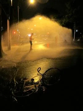 Man cools off under open fire hydrant in Brooklyn NY Stock Photos
