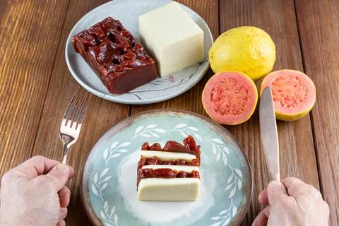 Man with a copper knife and fork ready to eat slices of guava sweet and curd  Stock Photos