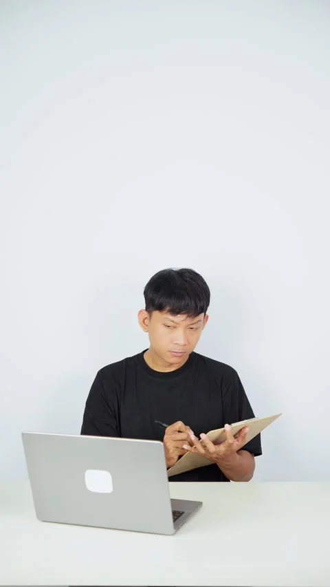 Man Copying Information From Laptop Into Notebook Video stock 347105403