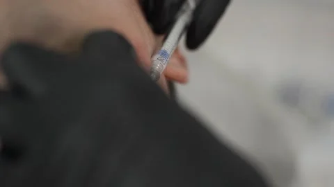 A man at a cosmetologists appointment injects Botox into his face Stock Footage 313695417