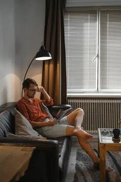 Man on the couch reading  Foto stock