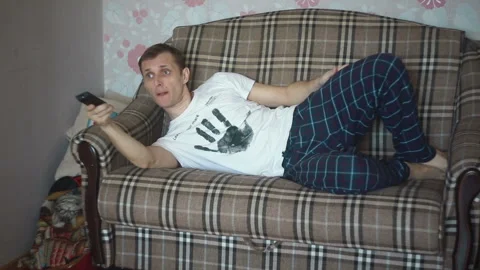 Man on the couch with remote control from the TV Stock Footage 87298056