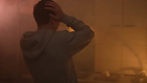 Man coughing and shielding face in a smoky kitchen during a fire emergency. Fire Stock Footage 305308048