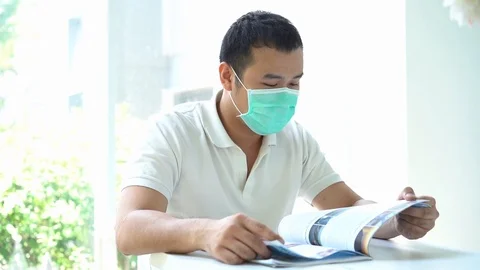 Man Coughing in His Mask while Reading slow motion 動画素材 126825852
