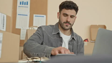 Man counting cash and sorting parcels, hand on bills at desk in a packing b.. Stockbeeldmateriaal 339174110