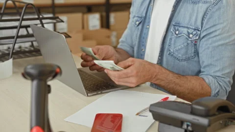 Man counting cash with bare hands beside laptop and packages at a parcel de.. Stock Footage 339169924