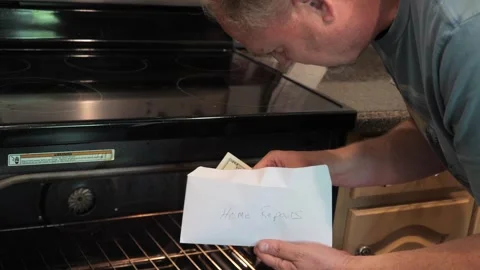 Man Counting Cash for Broken Oven Repair Cost in Kitchen Appliance Failure Stock Footage 332879273