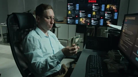 Man Counting Cash at Hacker Workstation with Multiple Screens Stock Footage 346708606