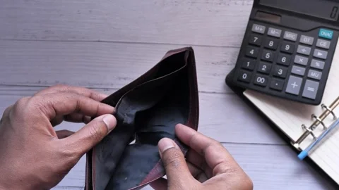 Man counting expenses and showing an empty money wallet on table with calculator Stock Footage 336450501