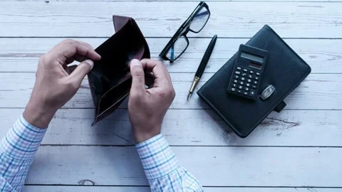 Man counting expenses and showing an empty money wallet on table with calculator Video stock 336450502