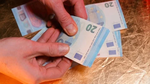 A man is counting with his hands banknotes of 20 euros on a yellow background. Stock Footage 124904857