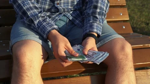 Man is counting money while sitting on a bench. 4k footage Stock Footage 160946874