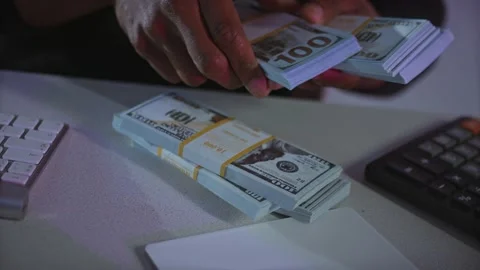 Man counting parcels of hundred dollars with a calculator and computer keyboard Stockbeeldmateriaal 238803836