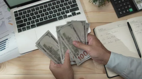 Man counting US dollar bills on a work desk with a laptop Stock-Footage 346771326