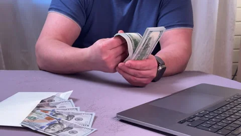 Man counting a wad of dollars sitting at a table side view, close-up on his hand Stock Footage 304755578