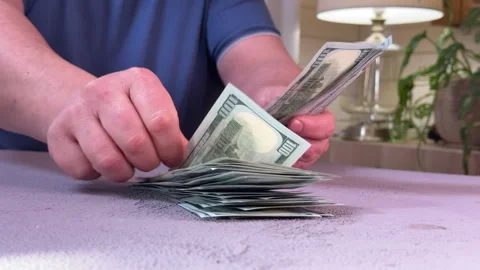 Man counting a wad of dollars sitting at a table side view, close-up on his hand Vídeo Stock 304755886