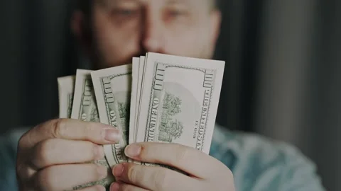 A man counts 100 dollar bills in front of his eyes. Indoor scene. Stock Footage 306622665
