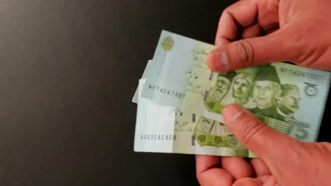 Man Counts 75 Rupee Notes Commemorating Pakistan’s 75th Independence Day Stock Footage 303347595