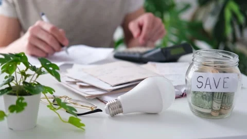 A man counts a bill on a calculator and a check for electricity on the table. Stock Footage 187471071