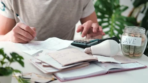 A man counts a bill on a calculator and a check for electricity on the table. Stock Footage 211617778