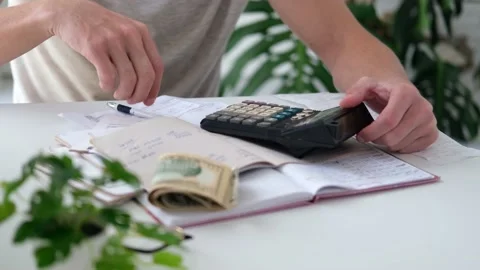 A man counts a bill on a calculator on the table. Stock Footage 187471557