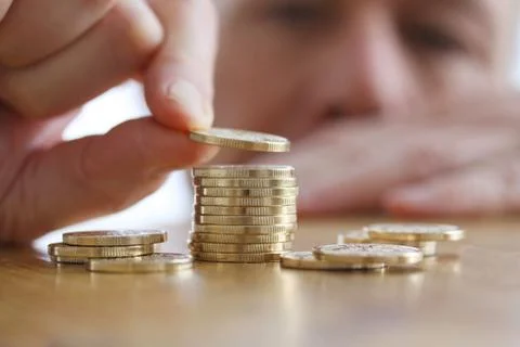 Man counts coins on a table. Close-up of hand putting a coin to stack of gold Stock Photos