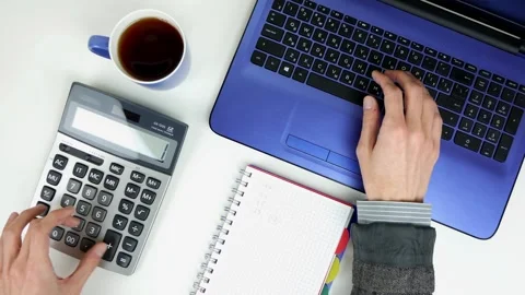 A man counts finances on a calculator and puts information into a laptop Stock Footage 101753057