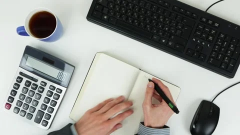 A man counts finances on a calculator and writes information in a notebook Stock Footage 101839346
